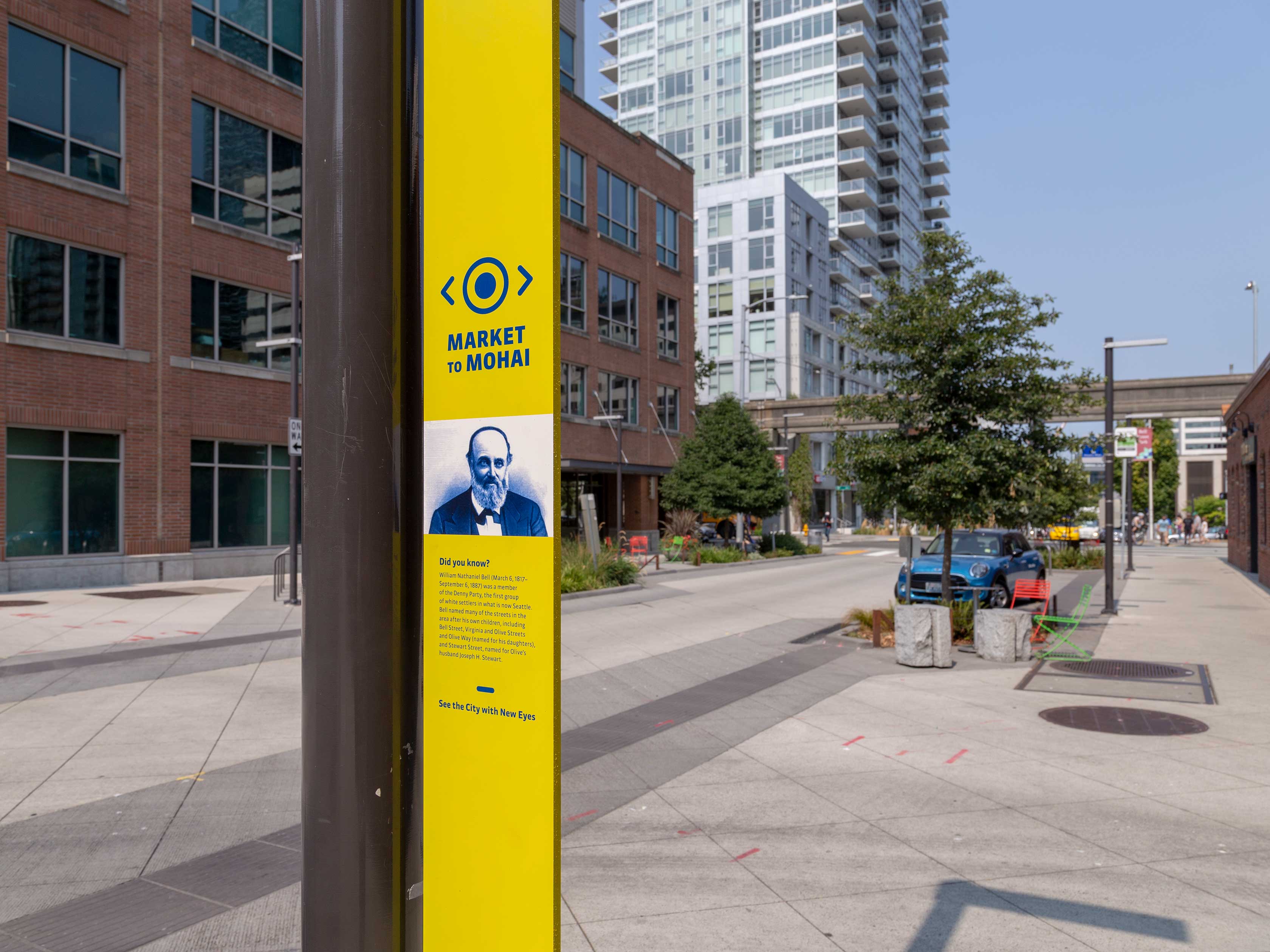 Yellow sign on a lamp post with information about Market to Mohai.