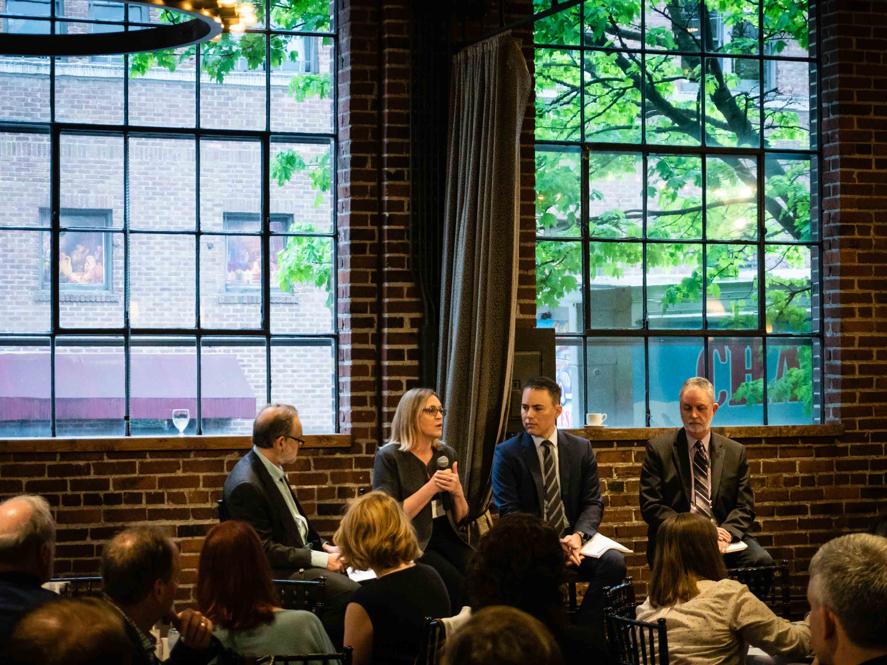 Panelists on stools in front of a crowd.