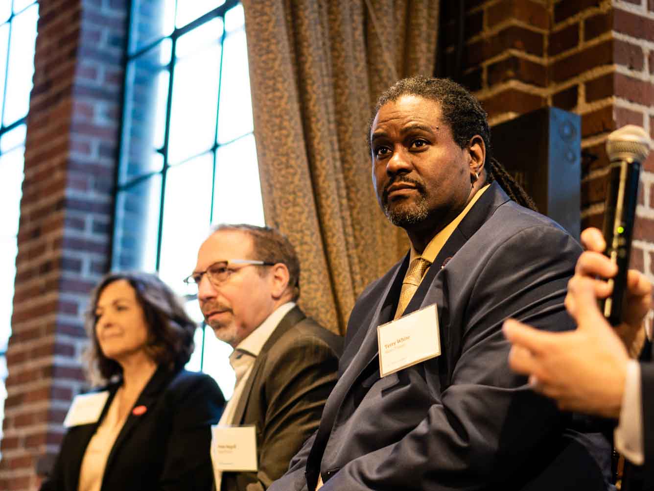 A woman and two men sit in front of an audience.