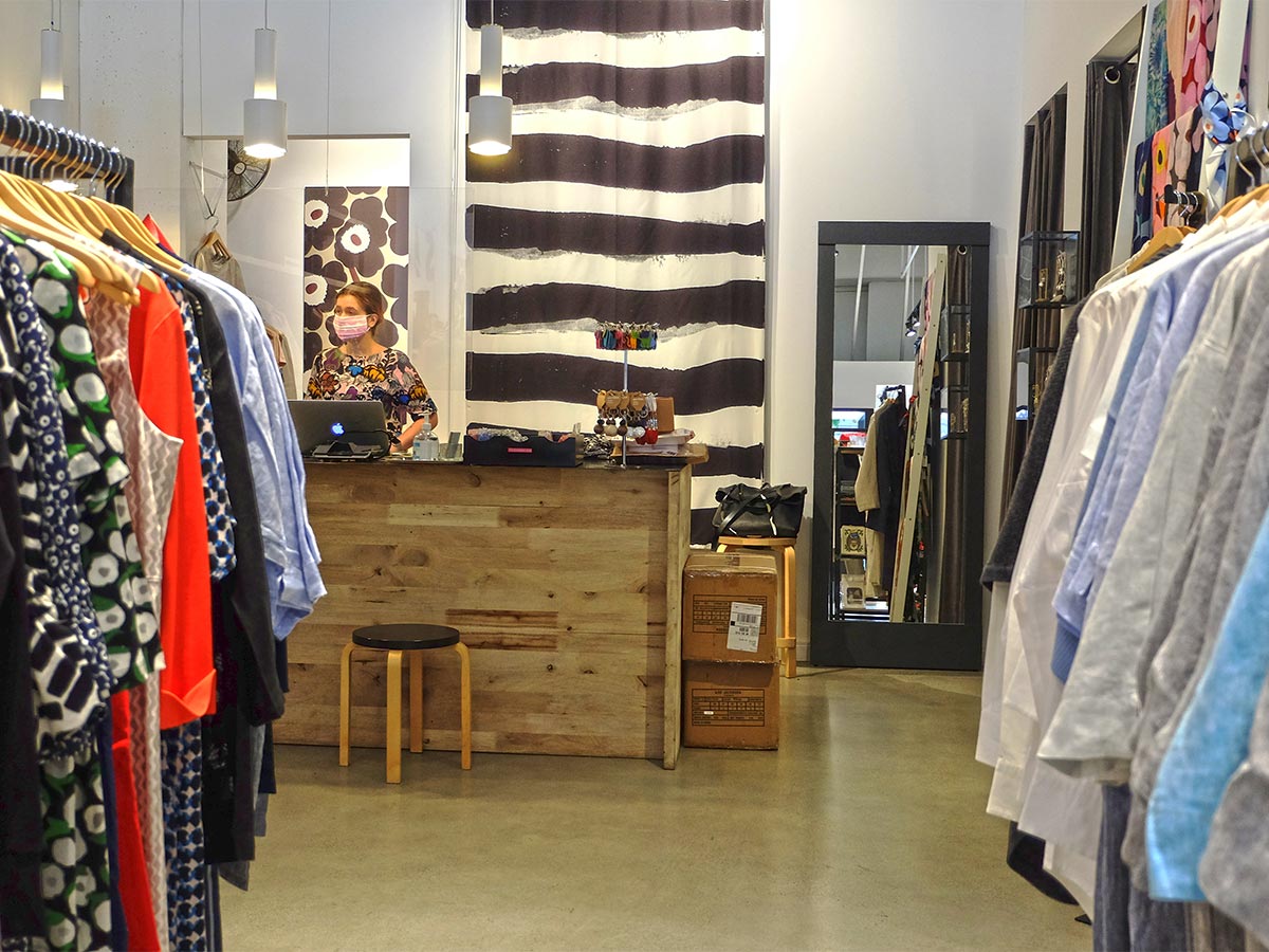 Woman wearing face mask behind clothing retail counter