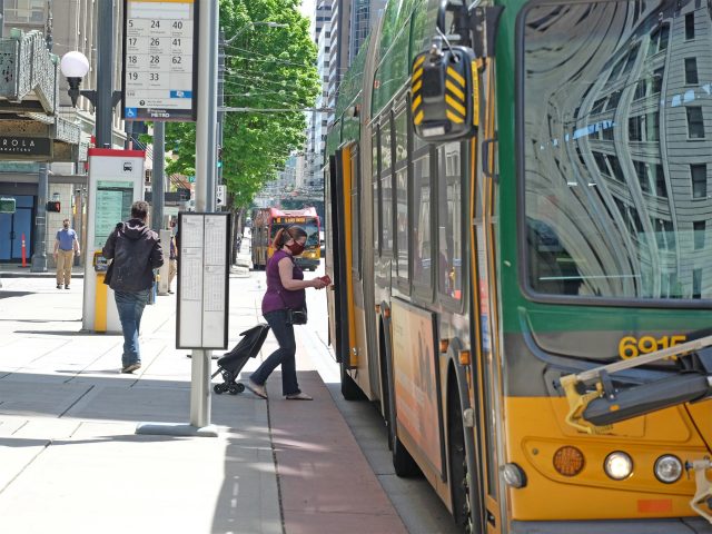 Woman wearing face mask boarding a bus in downtown Seattle