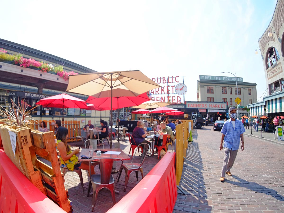 Man wearing mask walking past outdoor dining in Pike Place Market