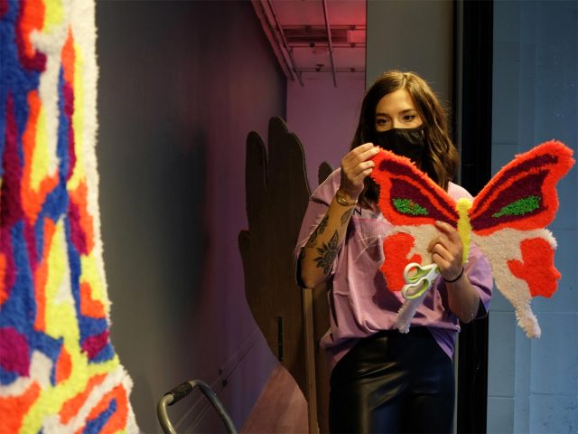 Masked artist working on a bright fiber butterfly