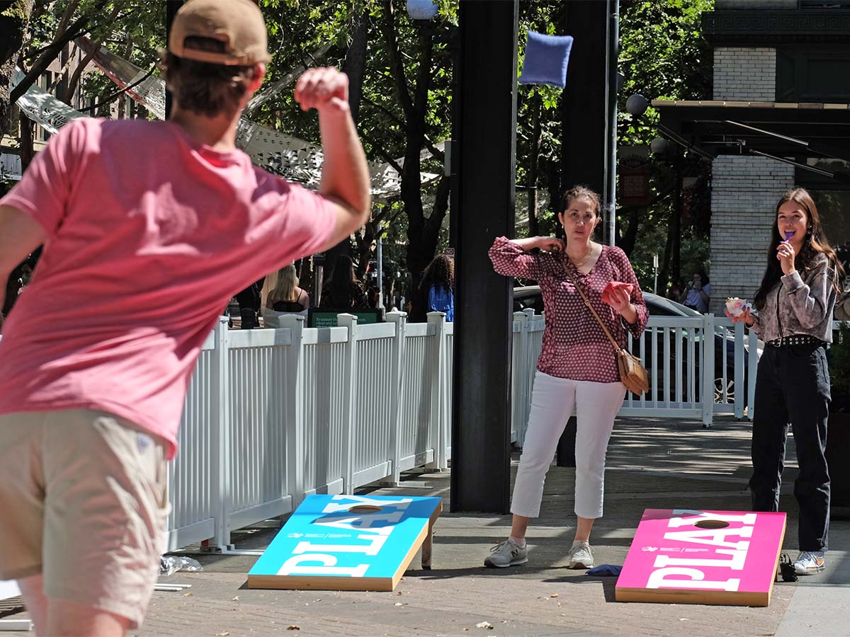 Friends playing corn hole in Occidental Square during DSA/MID's Welcome Back Weeks