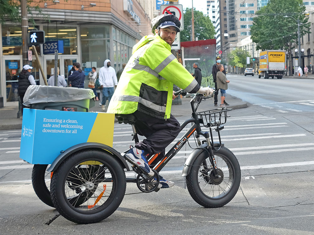 Smiling Downtown Ambassador riding a new trike, equipped to help make downtown Seattle clean, safe and welcoming for all