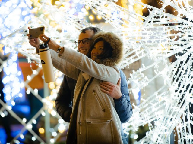 Couple taking a selfie with holiday lights