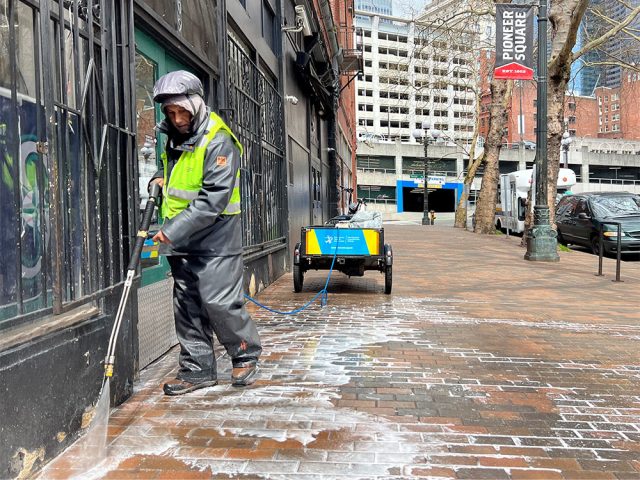 Downtown ambassador power washing the sidewalk in Pioneer Square