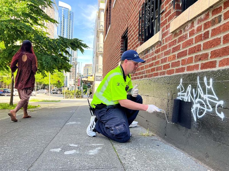 Downtown ambassador removing graffiti from the side of a building