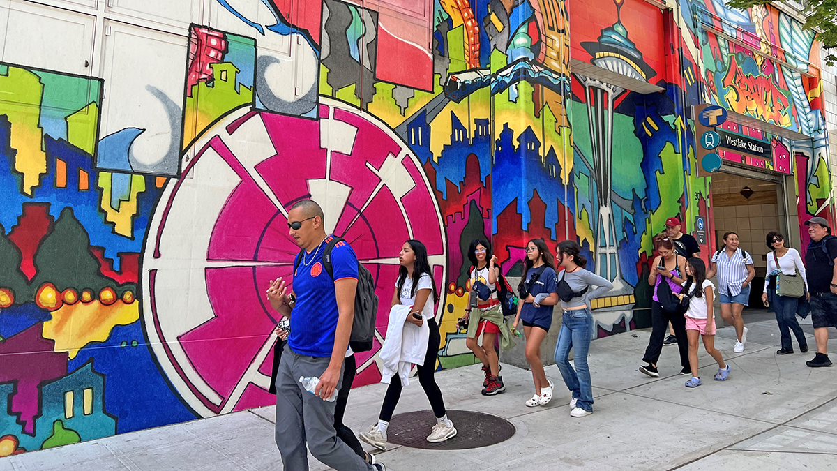 People walking in front of mural