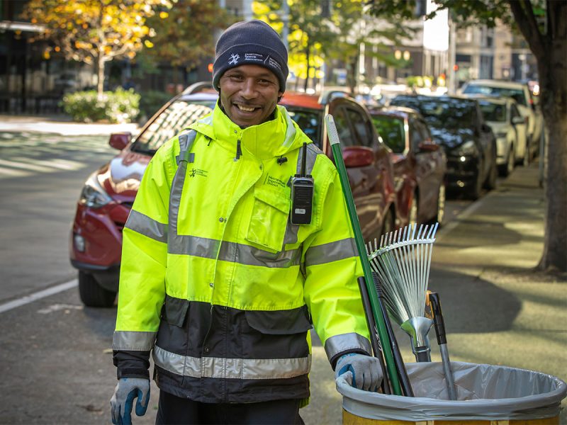 Downtown Clean Team ambassador smiling in a yellow reflective jacket