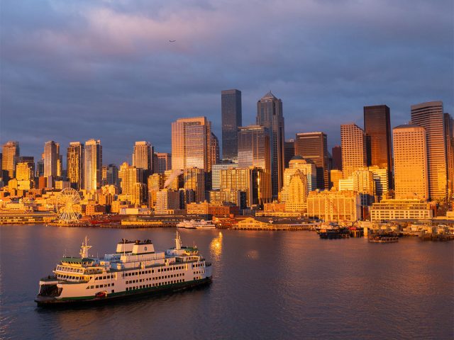 Seattle cityscape at sunset: waterfront, ferry, building and clouds.