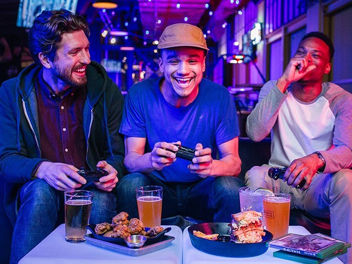 Friends playing games and enjoying food and drinks at GameWorks Seattle