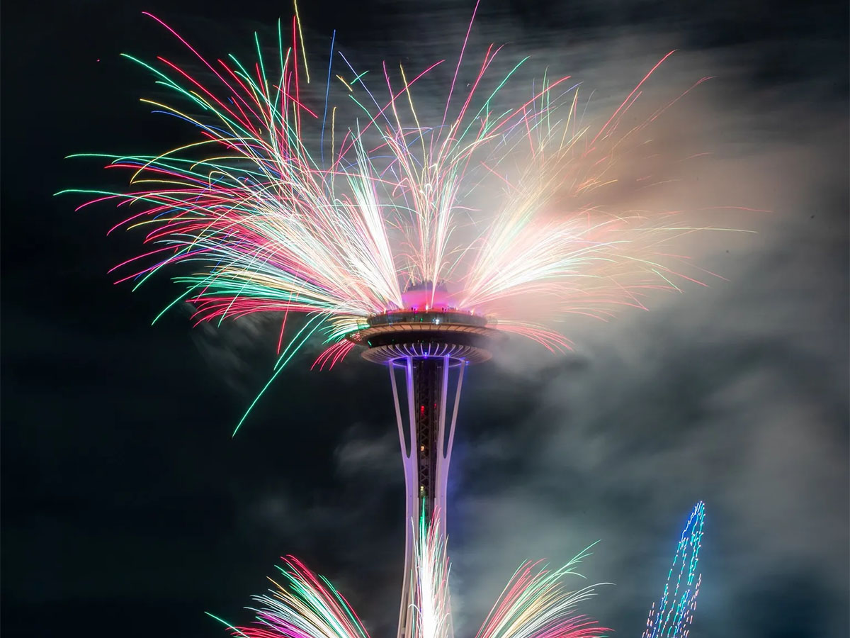 Fireworks and drones show at night at Space Needle. Bright lights and colors.