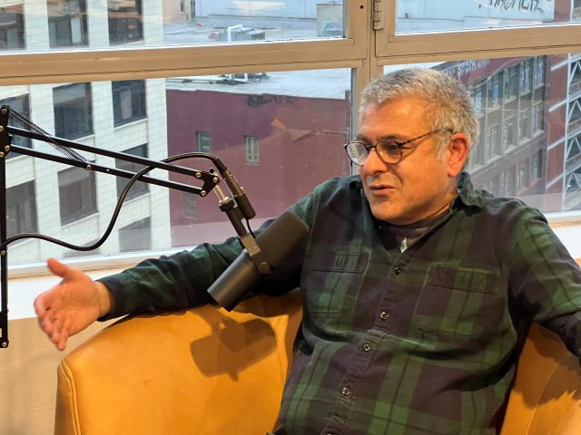 Sandeep Kaushik sits and speaks into a mic during a recording of the Seattle City Makers Podcast.