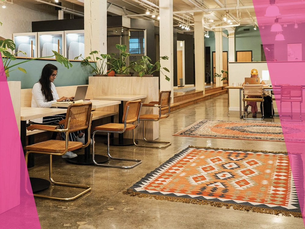 Woman working on a laptop at a table in a beautiful office building
