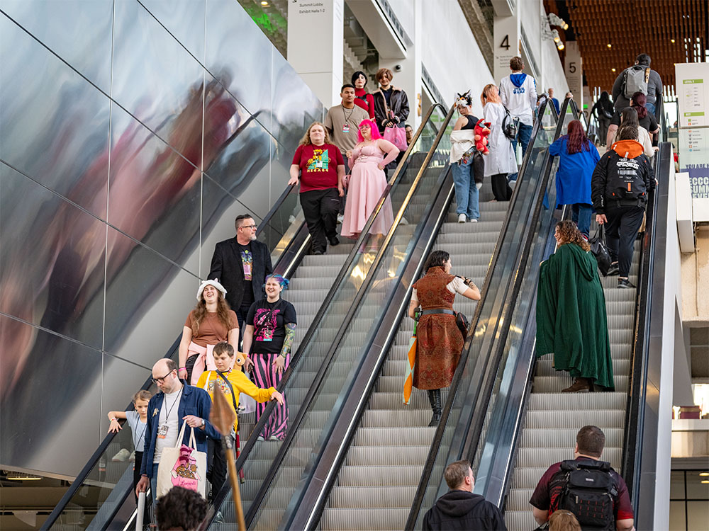 Comic Con visitors dressed in costume traveling up and down an escalator
