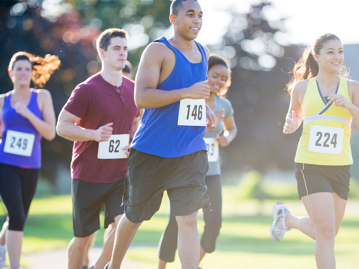 Smiling runners wearing race numbers on their shirts on a sunny day