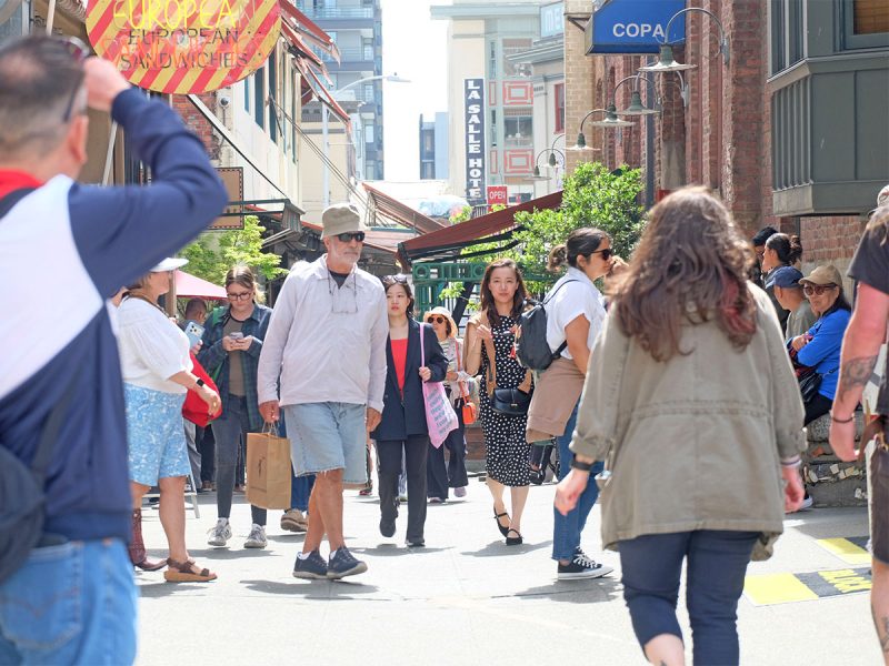 Tourists and local visitors on a sunny day in downtown Seattle at Post Alley in Pike Place Market