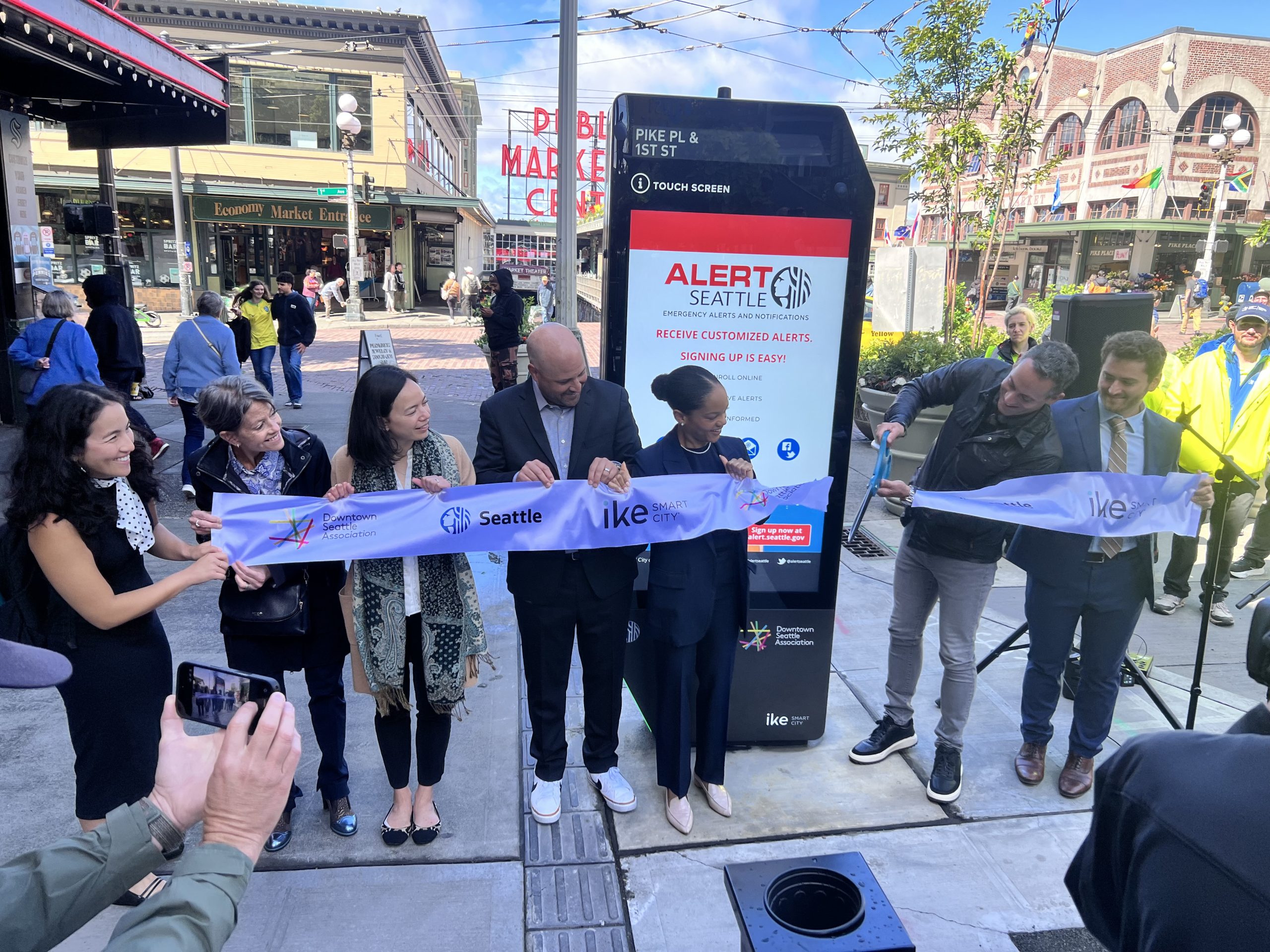 The ribbon is cut at the IKE kiosk unveiling at First & Pike on June 9, 2026.