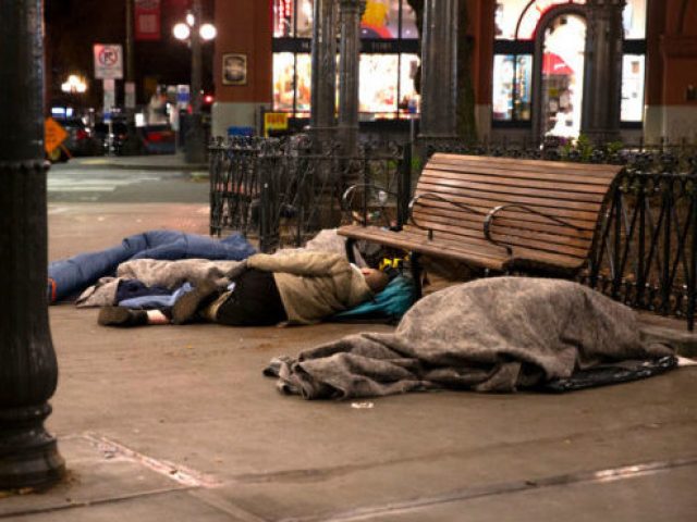 People sleep outside on a sidewalk on April 6, 2020, in Seattle, Washington. (Photo by Karen Ducey/Getty Images)